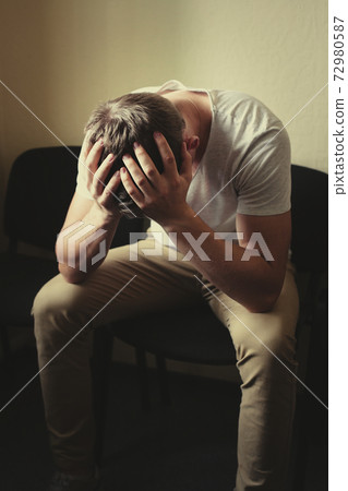 Men's problems. A young man sits on a chair and holds his head in his hands. Men's problems. A young man sits on a chair and holds his head in his hands. 72980587