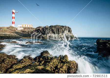 Beautiful scenic landscape with classic lighthouse on the coast and blue ocen and sky in background - concept of travel and vacation for tourism - wave and rocks 72981513