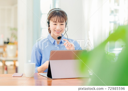 Woman in headset teleworking at home 72985596