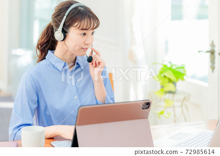 Woman in headset teleworking at home 72985614