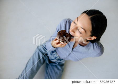 Portrait of rejoicing woman eats tasty donut at home. 72986127