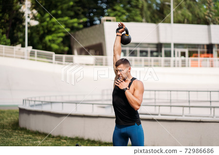 Sportive guy training with kettlebell. Strength and motivation. 72986686