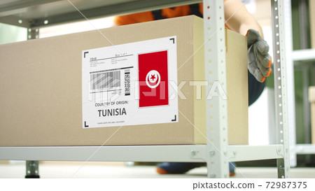 Cardboard box with products from Tunisia and storage employee Cardboard box with products from Tunisia and storage employee 72987375