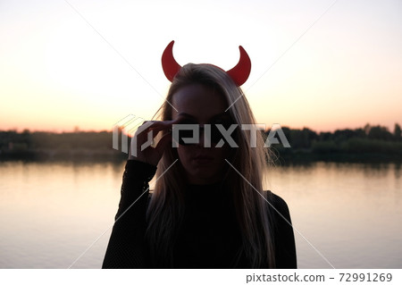 horned lady in sunglasses silhouette at sunset 72991269