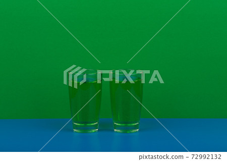 Two green drinks on blue table against green background with space for text Two green drinks on blue table against green background with space for text 72992132