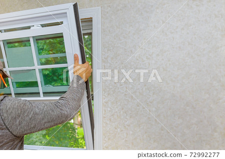 Worker in the installing new, windows in an house, with a new window in the home renovation living energy efficiency 72992277