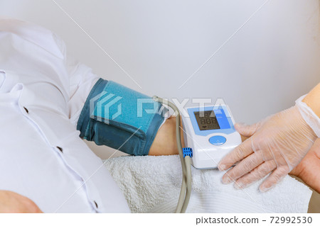 Female doctor with pressure to medical tonometer to measure pressure on the patient arm Female doctor with pressure to medical tonometer to measure pressure on the patient arm 72992530