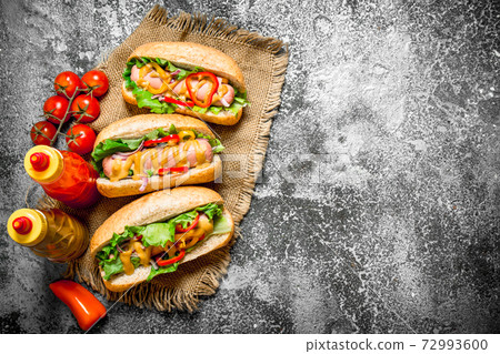 Street food. Delicious hot dogs with tomato sauce, mustard and herbs. 72993600