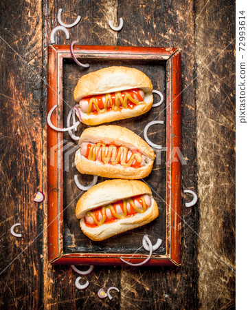 Hot dogs with mustard and tomato sauce on the Board. Hot dogs with mustard and tomato sauce on the Board. 72993614