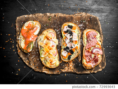 Sandwiches with seafood, meat and vegetables on fresh bread. Sandwiches with seafood, meat and vegetables on fresh bread. 72993643