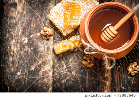 The honey in the pot with the nuts and cones. The honey in the pot with the nuts and cones. 72993646
