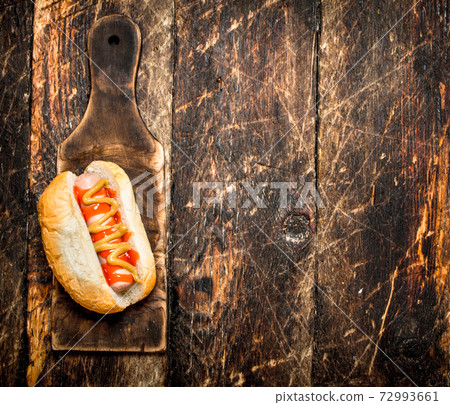 Hotdog with mustard on the old Board. Hotdog with mustard on the old Board. 72993661