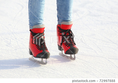 feet in red skates on an ice rink 72997888