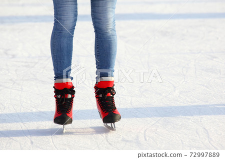 Female legs in skates on an ice rink 72997889