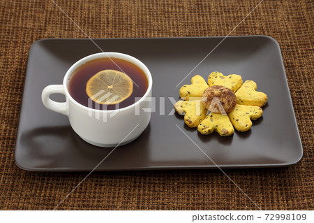 white cup of tea with lemon and biscuits 72998109
