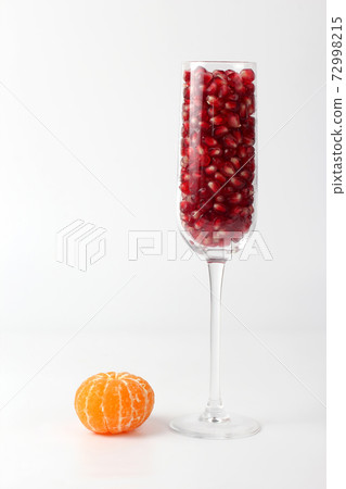 peeled mandarin and a glass of pomegranate on a white background peeled mandarin and a glass of pomegranate on a white background 72998215