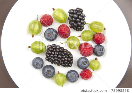 Assorted fresh different berries on a white plate. Assorted fresh different berries on a white plate. 72998258