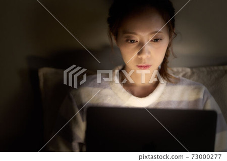 Young woman operating a PC in the bedroom Young woman operating a PC in the bedroom 73000277