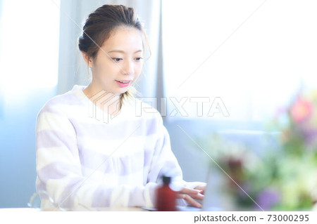 Young woman operating a personal computer in the room 73000295