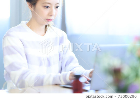 年輕女子在房間裡操作電腦 73000296