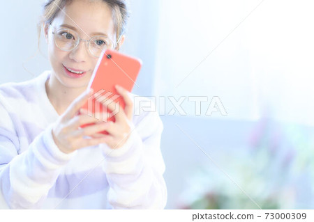 Young woman looking at the screen of a smartphone Young woman looking at the screen of a smartphone 73000309