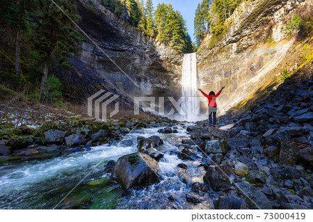 Girl watching a beautiful waterfall in Canadian Nature 73000419