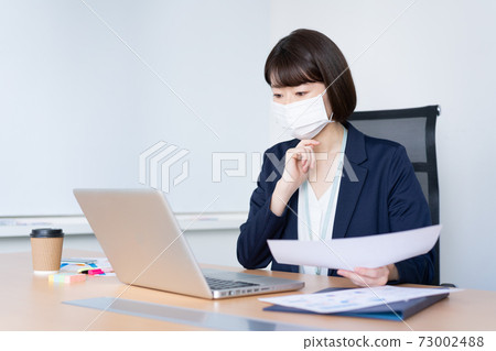 一個女人在辦公室用面具工作 一個女人在辦公室用面具工作 73002488