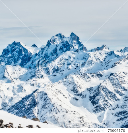 Snowy blue mountains in clouds Snowy blue mountains in clouds 73006178