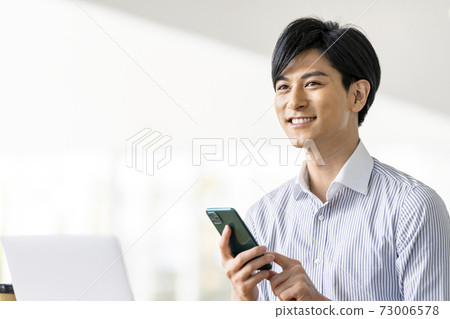A young man operating a smartphone A young man operating a smartphone 73006578