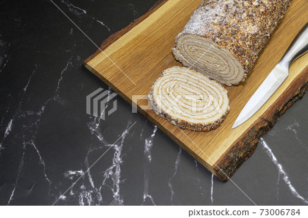 pastry roll on a wooden Board on black marble pastry roll on a wooden Board on black marble 73006784