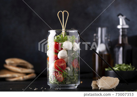 mozzarella with cherry tomatoes and arugula in a glass jar mozzarella with cherry tomatoes and arugula in a glass jar 73007353
