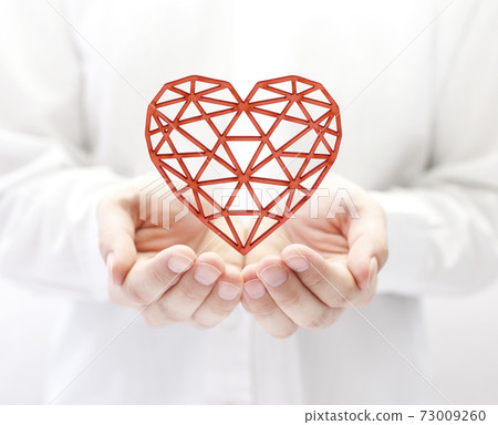 Red openwork heart in hands 73009260