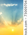 sky and clouds nature background, bright sunset with orange sun light in blue sky with soft clouds and sun rays 73009704