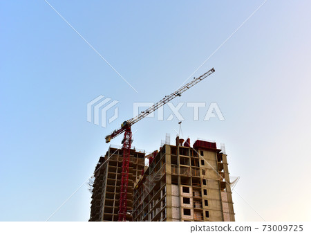 Tower crane construct of new multi-storey buildings on construction site. Residential building Tower crane construct of new multi-storey buildings on construction site. Residential building 73009725