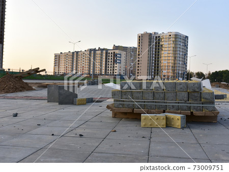Laying paving slabs in pedestrian zone at construction site. Laying paving slabs in pedestrian zone at construction site. 73009751