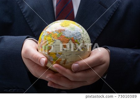 Man holding an earth globe model in his hands 73010389