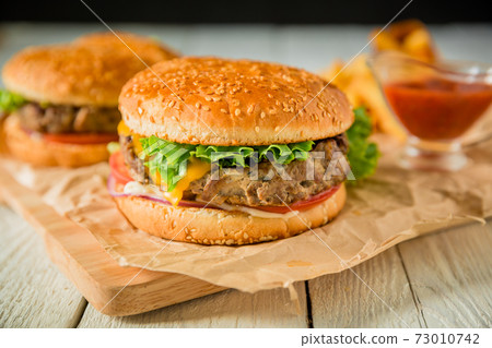 Fresh american hamburger with beef and tomato sauce on wooden board Fresh american hamburger with beef and tomato sauce on wooden board 73010742