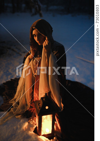 Fantasy night shot of young woman sitting with vintage lantern looking at you. Medieval fairytale concept Fantasy night shot of young woman sitting with vintage lantern looking at you. Medieval fairytale concept 73010803