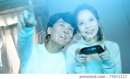 Young men and women enjoying video games in the room Young men and women enjoying video games in the room 73011217