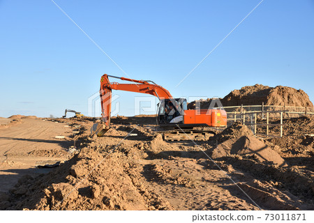 Excavator Working On Road Construction. Backhoe on Earthworks. Excavator Working On Road Construction. Backhoe on Earthworks. 73011871