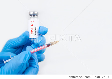 Doctor or scientist holding vial dose of COVID-19 vaccine with syringe against white background with copy space for text - prevention coronavirus, global vaccination concept. Selective focus Doctor or scientist holding vial dose of COVID-19 vaccine with syringe against white background with copy space for text - prevention coronavirus, global vaccination concept. Selective focus 73012494