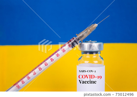 COVID-19 vaccine vial against Ukrainian flag on blue background with copy space for text - coronavirus vaccine doses, vaccination in Ukraine concept. Selective focus COVID-19 vaccine vial against Ukrainian flag on blue background with copy space for text - coronavirus vaccine doses, vaccination in Ukraine concept. Selective focus 73012496