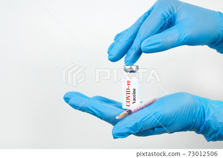 Female scientist or doctor hands holding vial dose of COVID-19 vaccine with syringe against white background with copy space - prevention coronavirus, global vaccination concept. Selective focus Female scientist or doctor hands holding vial dose of COVID-19 vaccine with syringe against white background with copy space - prevention coronavirus, global vaccination concept. Selective focus 73012506