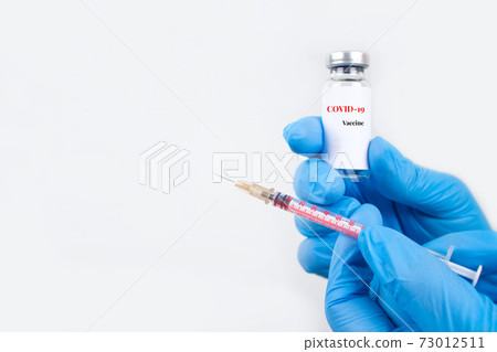 Doctor or scientist holding vial dose of COVID-19 vaccine with syringe against white background with copy space - prevention coronavirus, global vaccination concept. Selective focus Doctor or scientist holding vial dose of COVID-19 vaccine with syringe against white background with copy space - prevention coronavirus, global vaccination concept. Selective focus 73012511