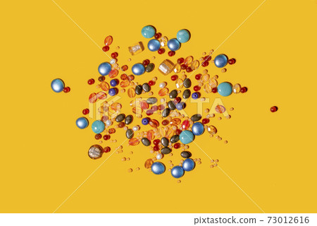 Multi coloured beads on yellow background. Multi coloured beads on yellow background. 73012616