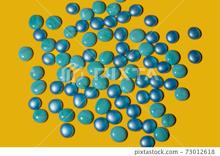 Blue and turquoise glass pebbles on a yellow background Blue and turquoise glass pebbles on a yellow background 73012618