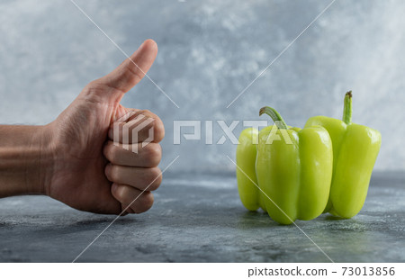 Man gesturing thumb up yo the green sweet pepper 73013856