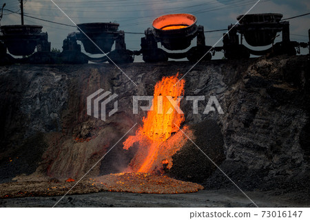 Colorful stream of molten metal at a steel mill. Blast furnace slag at the iron foundry Colorful stream of molten metal at a steel mill. Blast furnace slag at the iron foundry 73016147