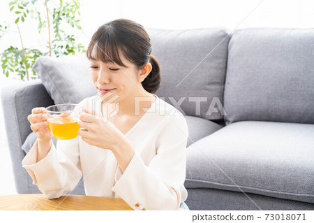 Woman drinking tea in the living room Woman drinking tea in the living room 73018071