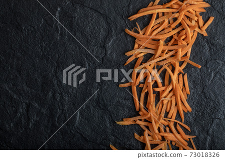 Julienne of fresh organic carrot over black background Julienne of fresh organic carrot over black background 73018326